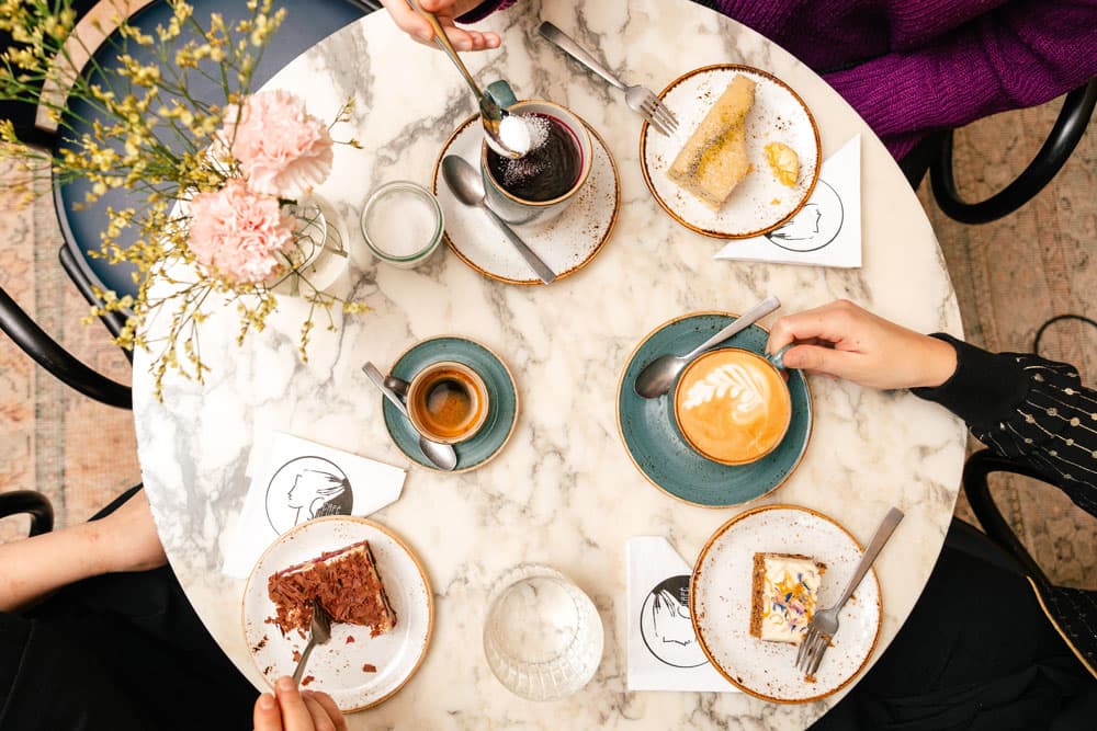 Ein Tisch von oben mit Kuchentellern, Kaffeetassen und einer Blumenvase