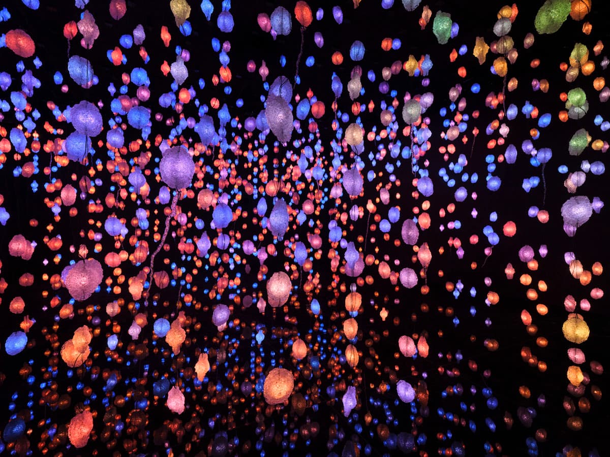 Viele bunte Lichter hängen in einem komplett dunklen Raum