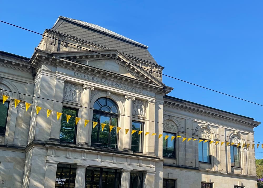 Ausschnitt der Kunsthallen-Fassade mit blauem Himmel und gelber Fähnchen-Girlande